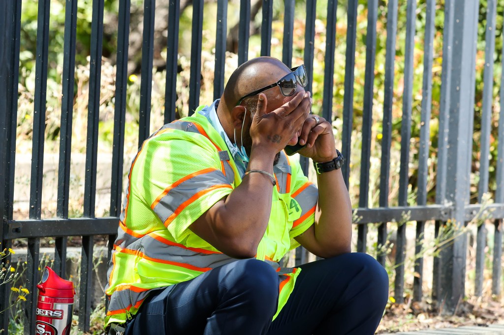 A man cries while sitting on the sidewalk on North First Street near the scene of a shooting at the Valley Transportation Authority's (VTA) light-rail facility in San Jose, Calif., on Wednesday, May 26, 2021.