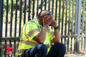 A man cries while sitting on the sidewalk on North First Street near the scene of a shooting at the Valley Transportation Authority's (VTA) light-rail facility in San Jose, Calif., on Wednesday, May 26, 2021.