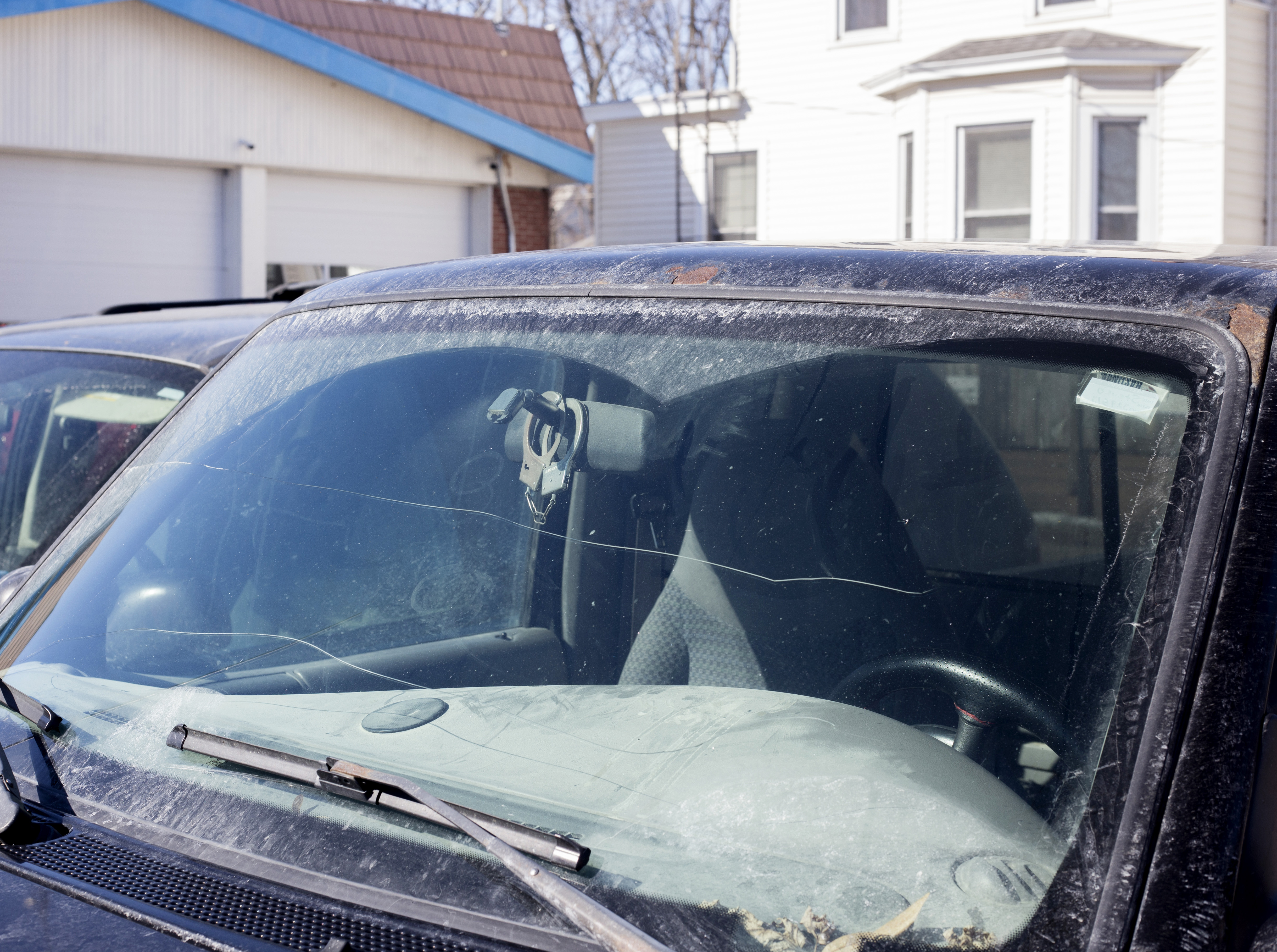 front window of a car with hand cuff hanging behind the rearview mirror