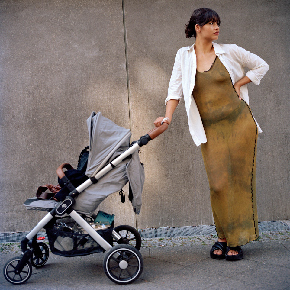 Lucia Jost, Motherhood – A Mother's Hood – Mujer de cabello castaño con un maxi vestido terroso, posando junto a una carriola 030.jpeg