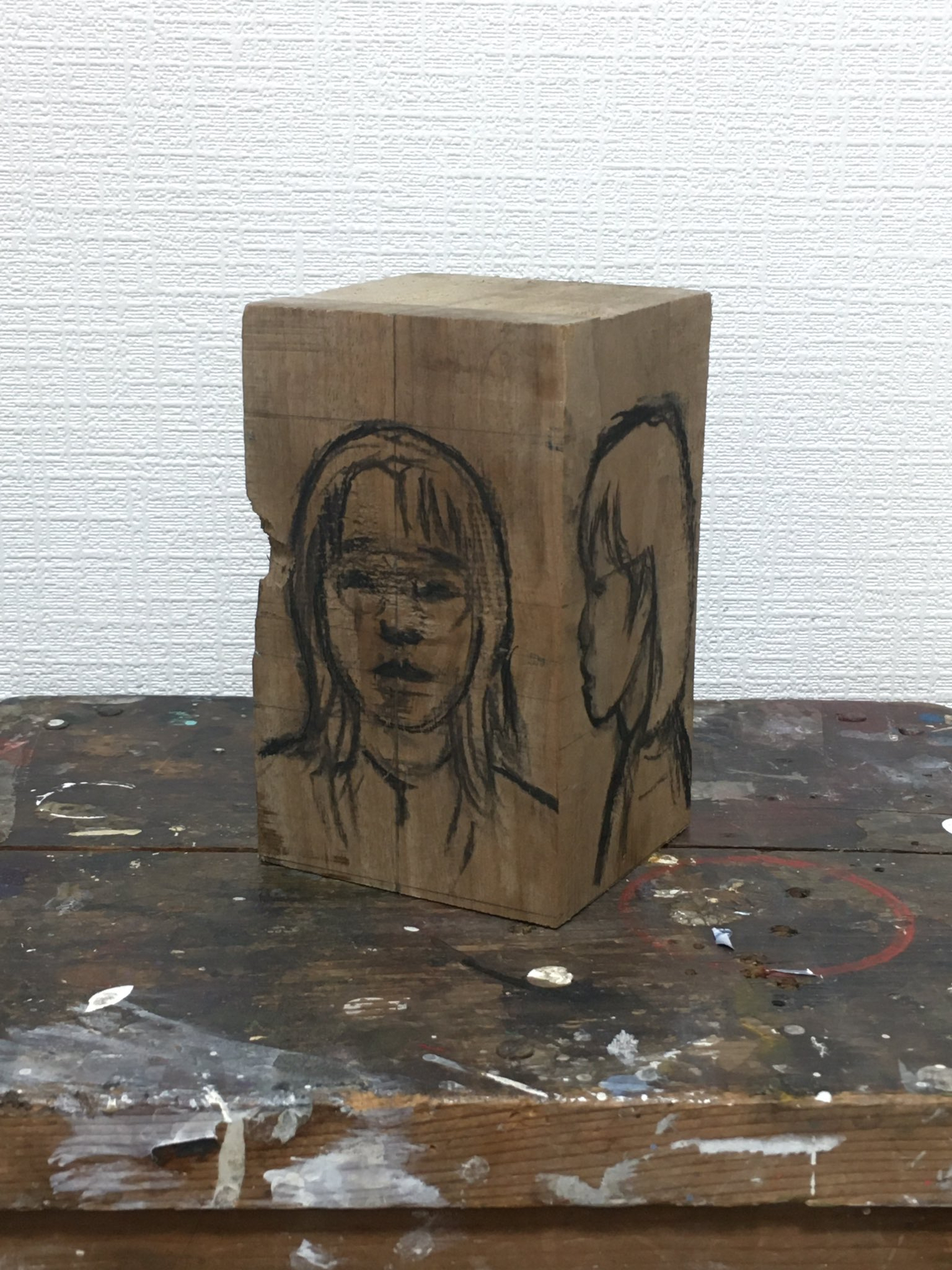 Houten blok met daarop een schets van de buste van een meisje