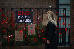 A woman walks past a placard saying 'End Rape Culture' attached to the fence outside James Allen's Girls' School (JAGS)