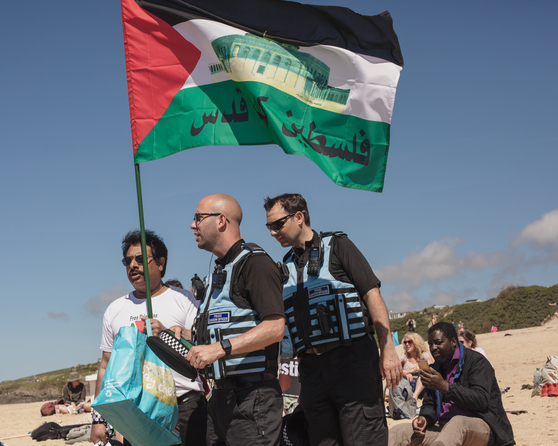One member of the group chats with police liaison officers whilst holding a Palestinian flag.