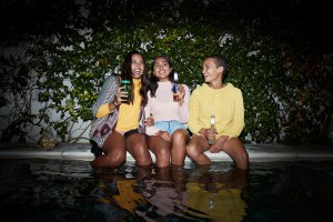 three people with drinks at a pool