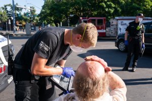 paramedic helps patient suffering from heat stroke during heat wave
