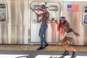A couple in a music group dancing beside a train.