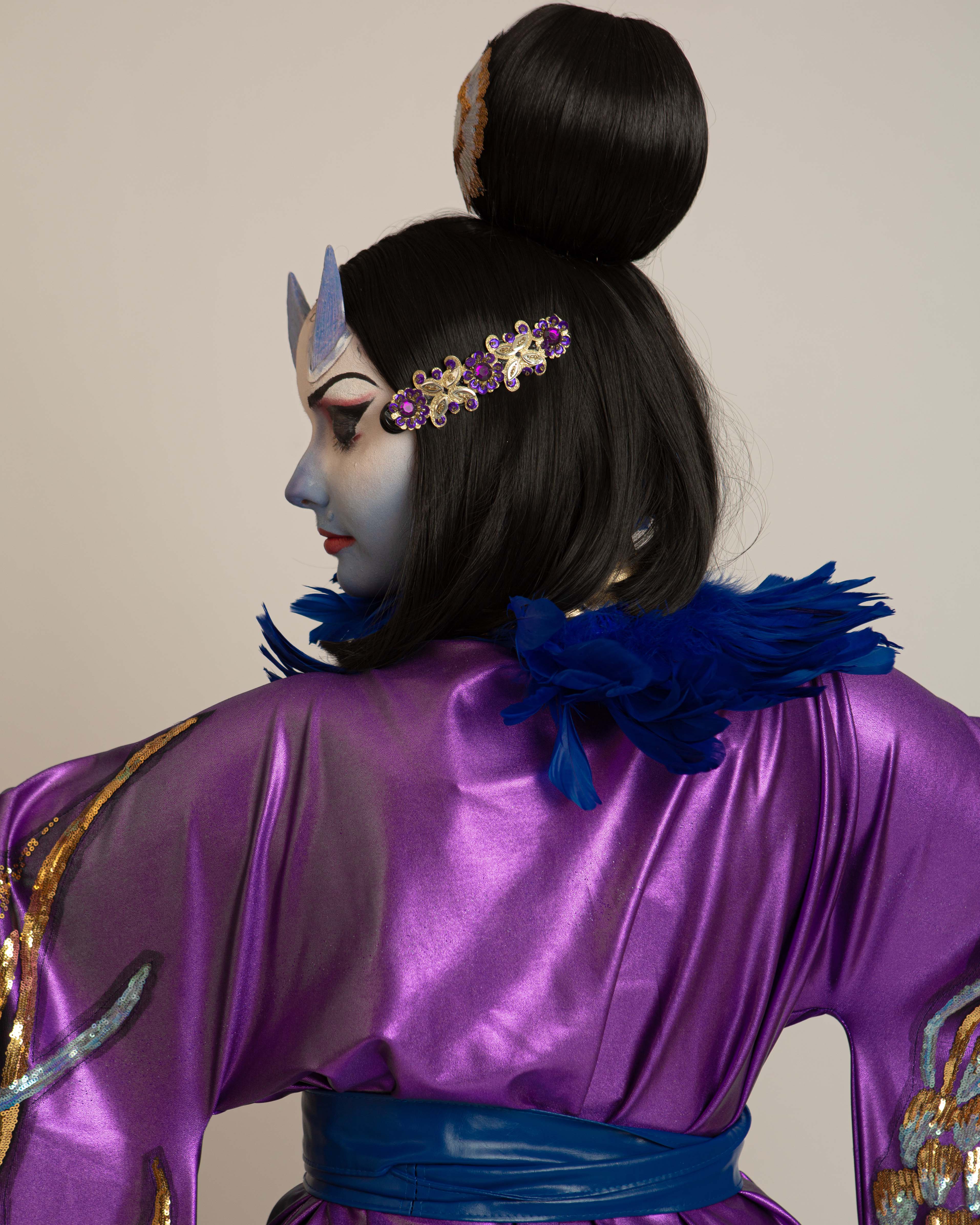 Iris de Grauw, Queer Arcana. Female character wearing a purple kimono with gold accents, a black bob wig with a ball on top, white and blue face paint and horns.