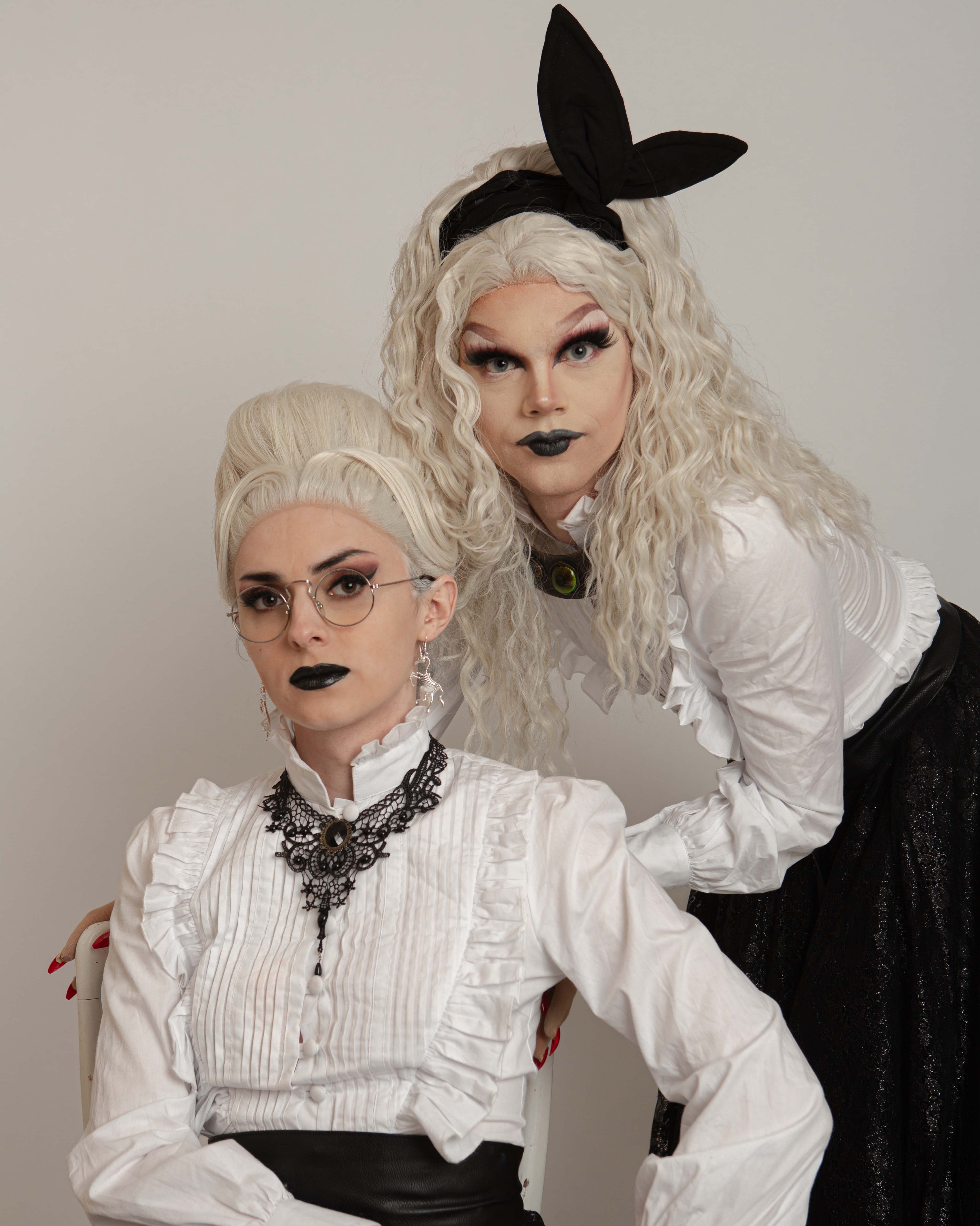 Freya Terpstra, Derk Over, Queer Arcana – Two female characters wearing platinum blonde wigs, a frilly white shirt, black skirts and black lips.