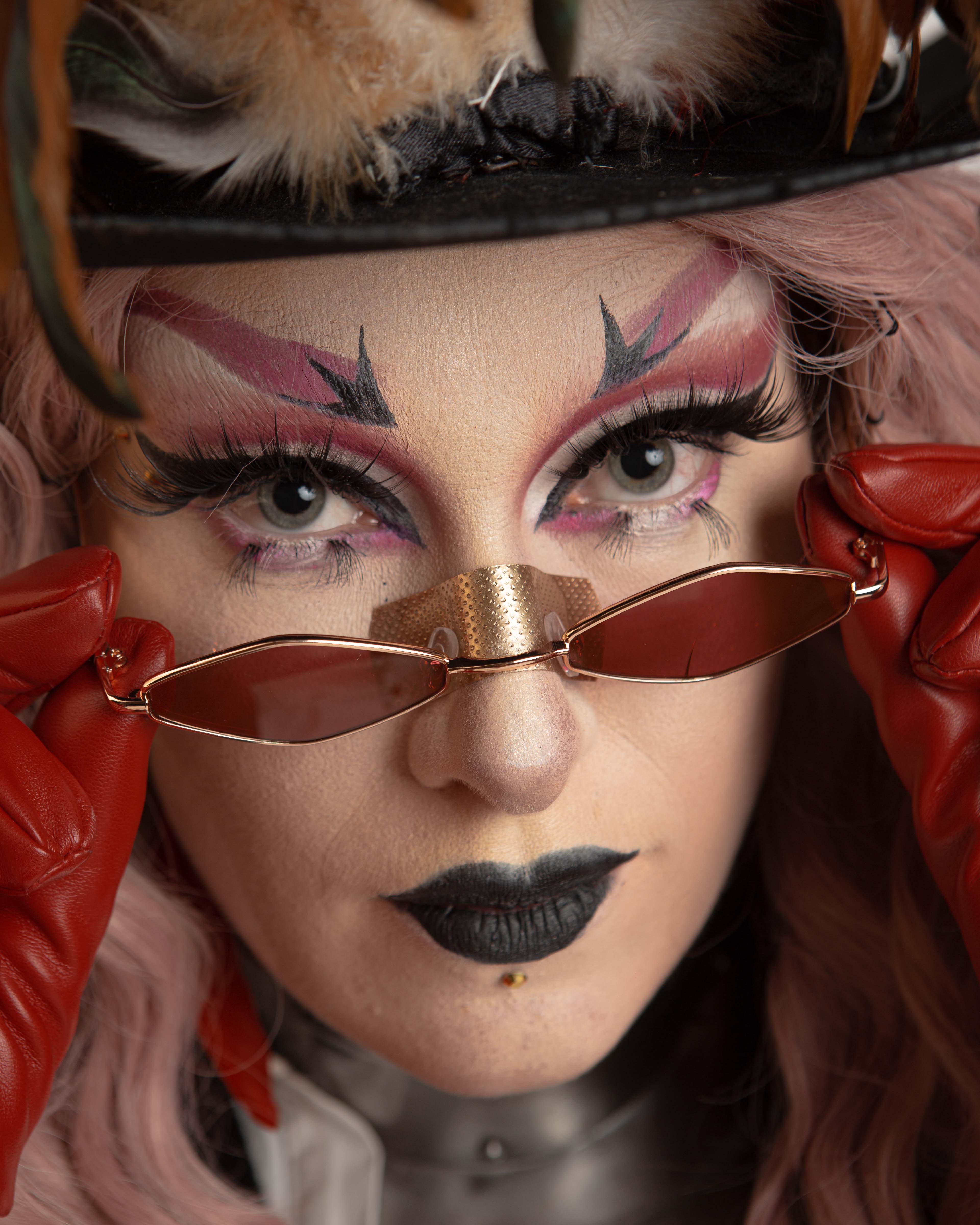 Tiva Pam, Queer Arcana – close up of the character face, revealing an elaborate purple and black make up look and golden