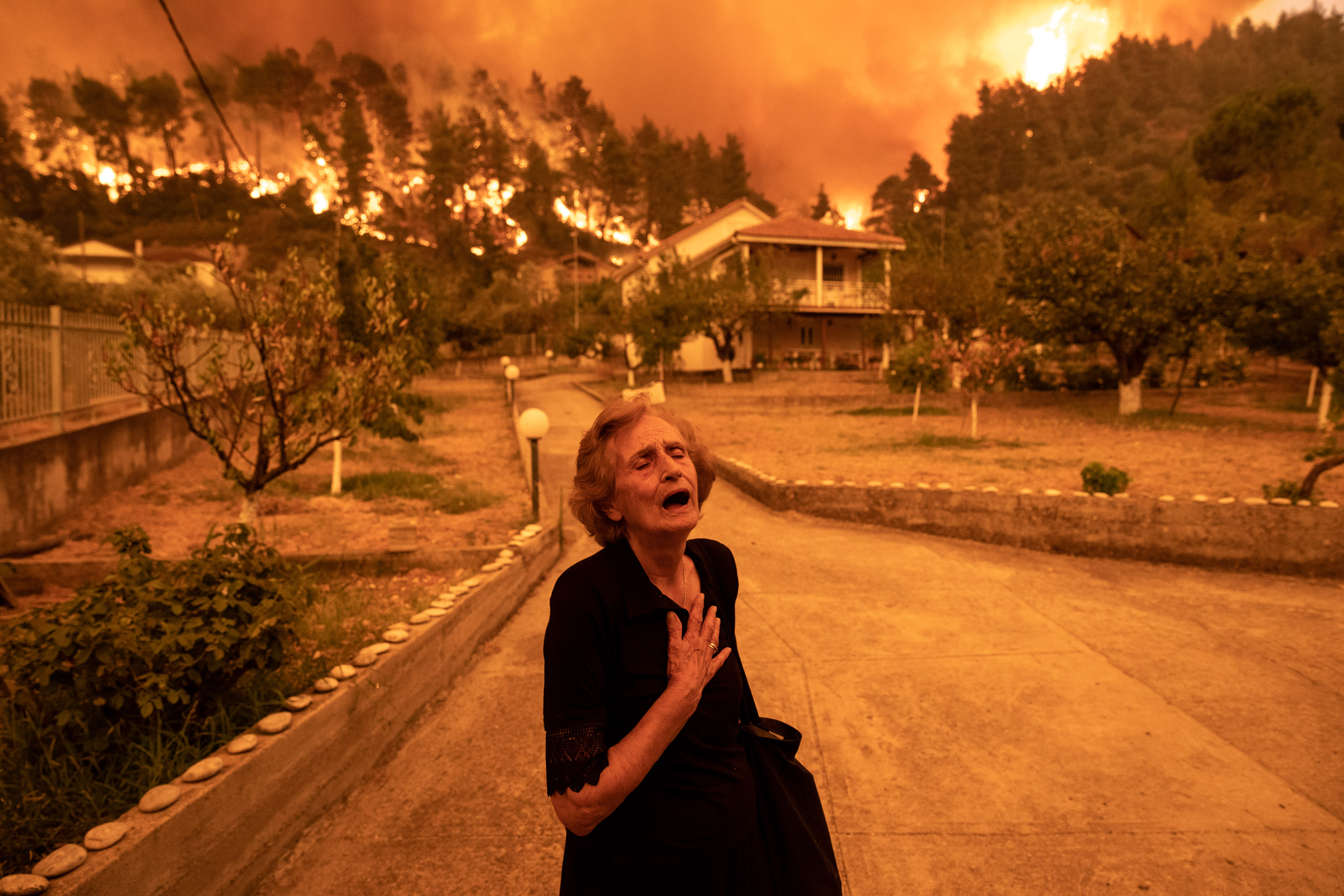 A woman reacts as a wildfire approaches her house in the village of Gouves, on the island of Evia, Greece, on Sunday. Photo: Konstantinos Tsakalidis/Bloomberg via Getty Images