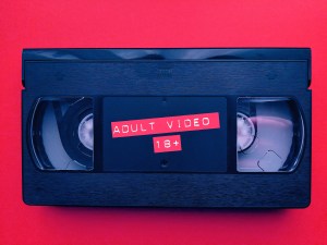 A VHS tape that says "ADULT VIDEO 18+" on the label.