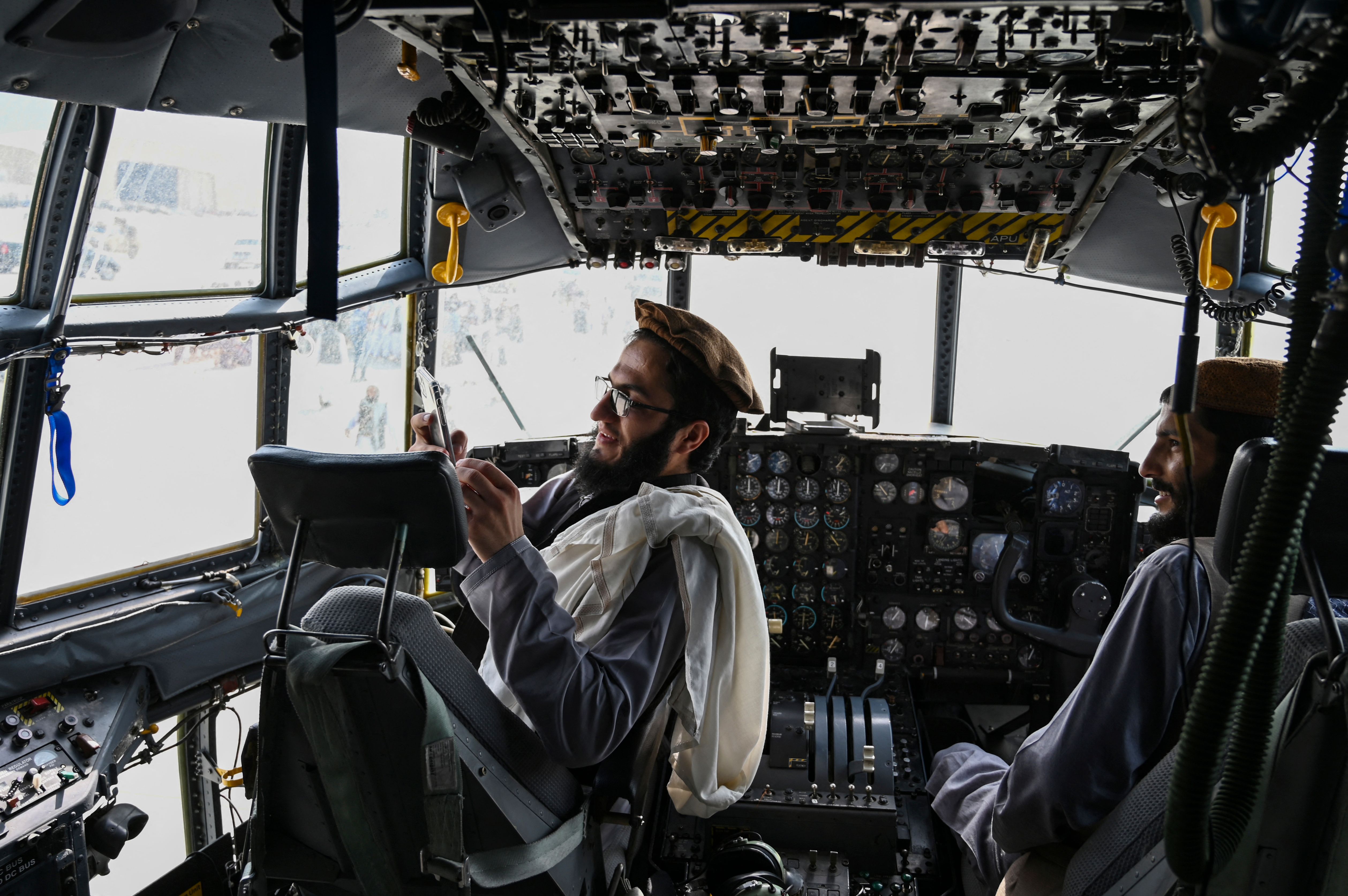 Taliban fighters sit in the cockpit of an abandoned Afghan Air Force aircraft at Kabul's airport at the end of August, after US troops withdrew. Photo: WAKIL KOHSAR/AFP via Getty Images