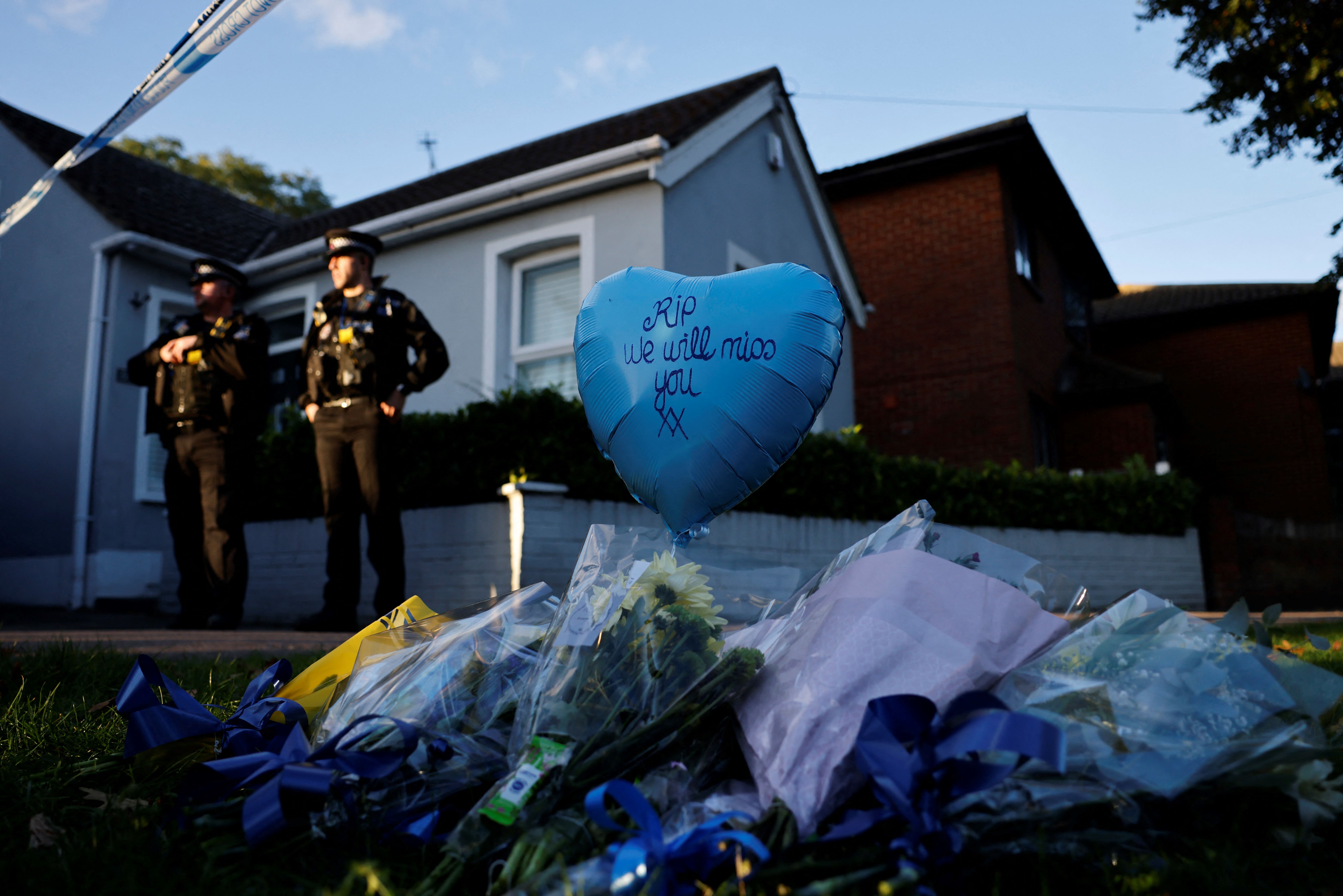 Floral tributes are placed near the scene as police officers stand guard. Photo: TOLGA AKMEN/AFP via Getty Images