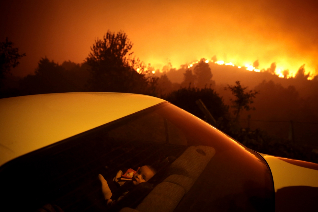In “Portugal Forest Fire” by Nuno André Ferreira from Portugal, a forest fire rages about a 100km from Porto, as a child sits in a nearby car child sits inside a car. Every year in Portugal thousands of hectares of forest burn out of control. Photo: Nuno André Ferreira
