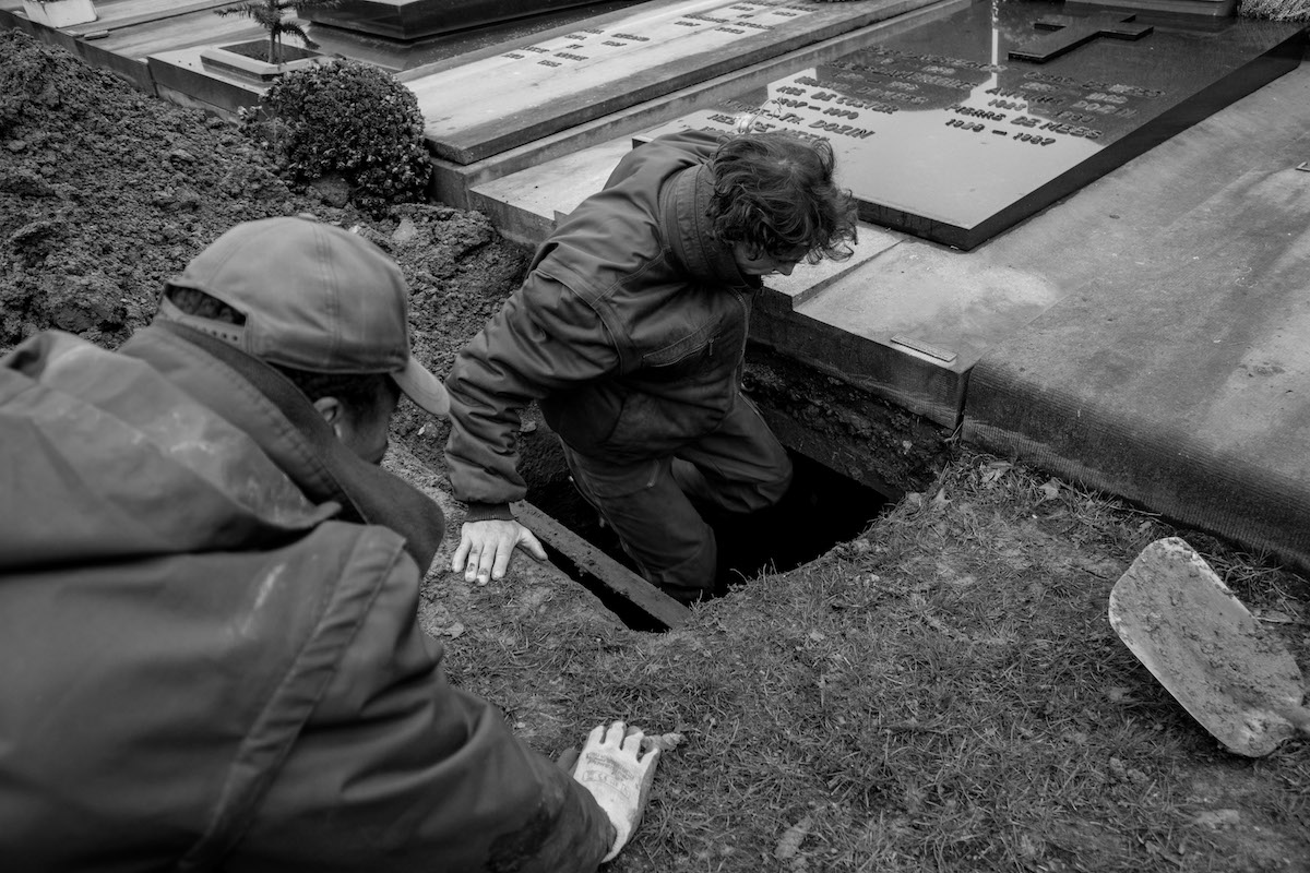 Jacques Vermeer, Patrick, cemetery - Black and white photo of a man lowering himself into a grave.