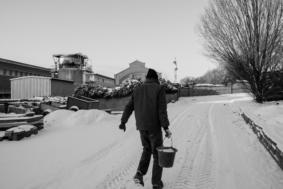 Jacques Vermeer, Patrick, cemetery - Black and white photo of a man carrying a bucket in a snowy cemetery, his back to the camera.