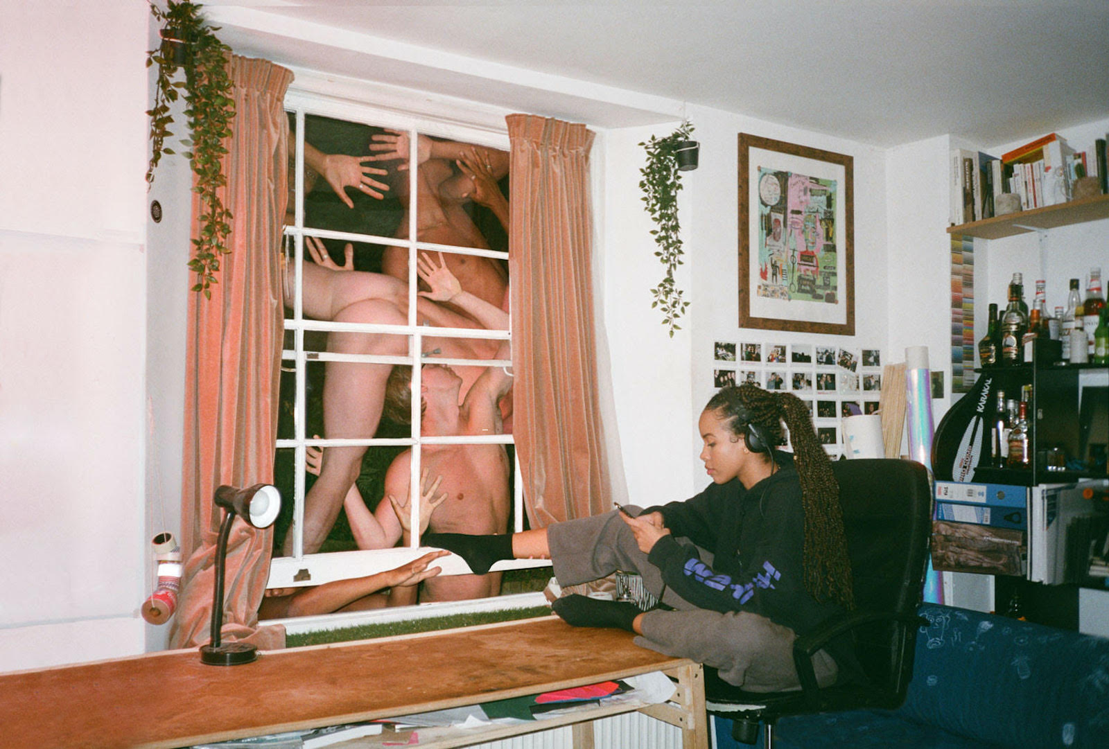 A black person with braids looking at their phone next to a window of naked people