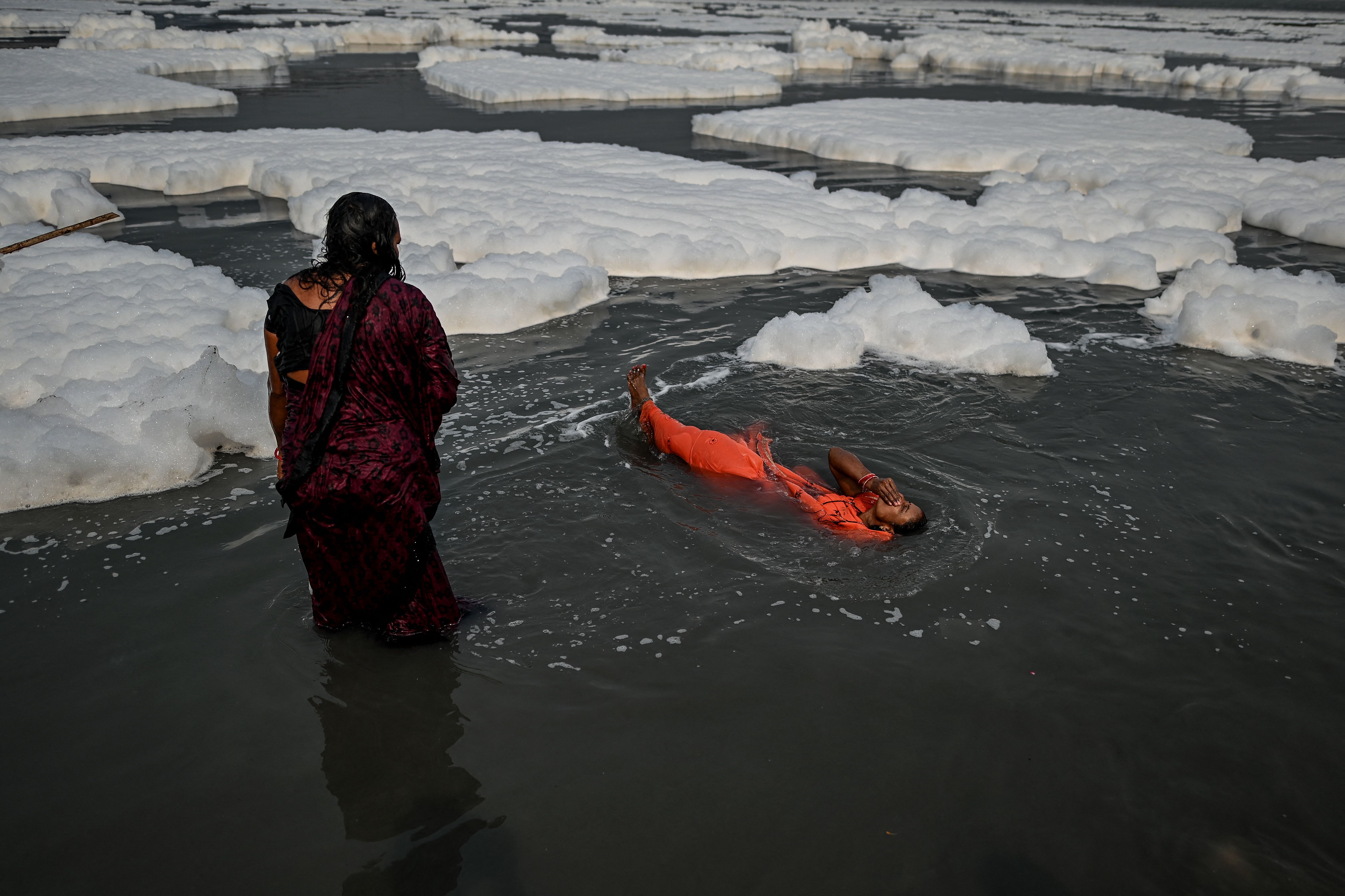 Alcune persone fanno il bagno in uno dei più inquinati fiumi dell'India. Foto: Sajjad Hussain / AFP via Getty + Sunil Ghosh / Hindustan Times via Getty