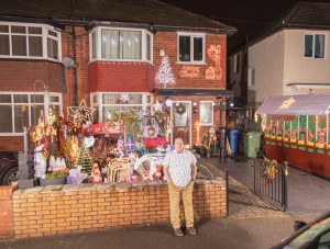 Owner stands in front of his house covered in Christmas lights