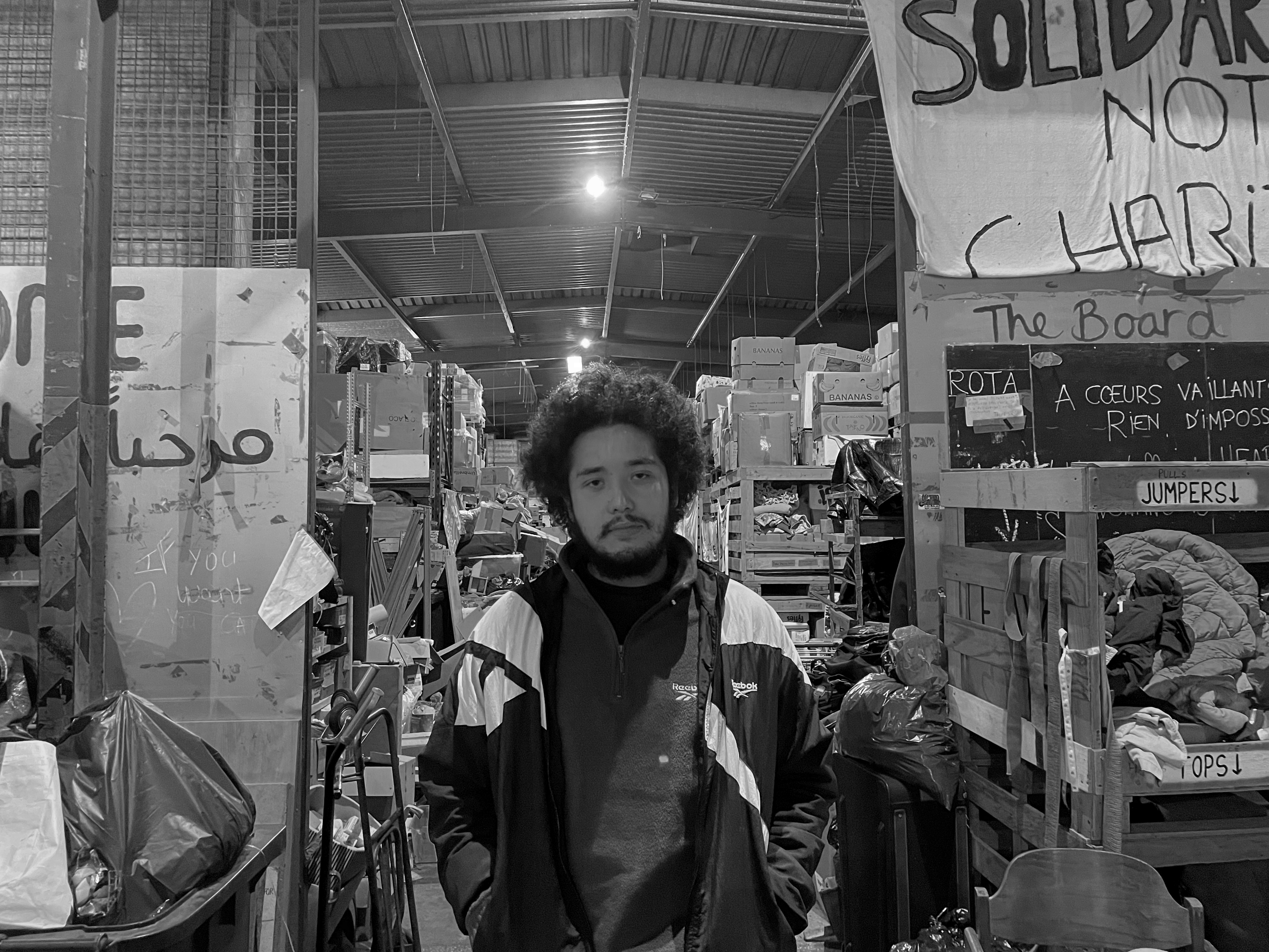 Calais, refugee camps - Black and white photo a man in a well-stocked warehouse.