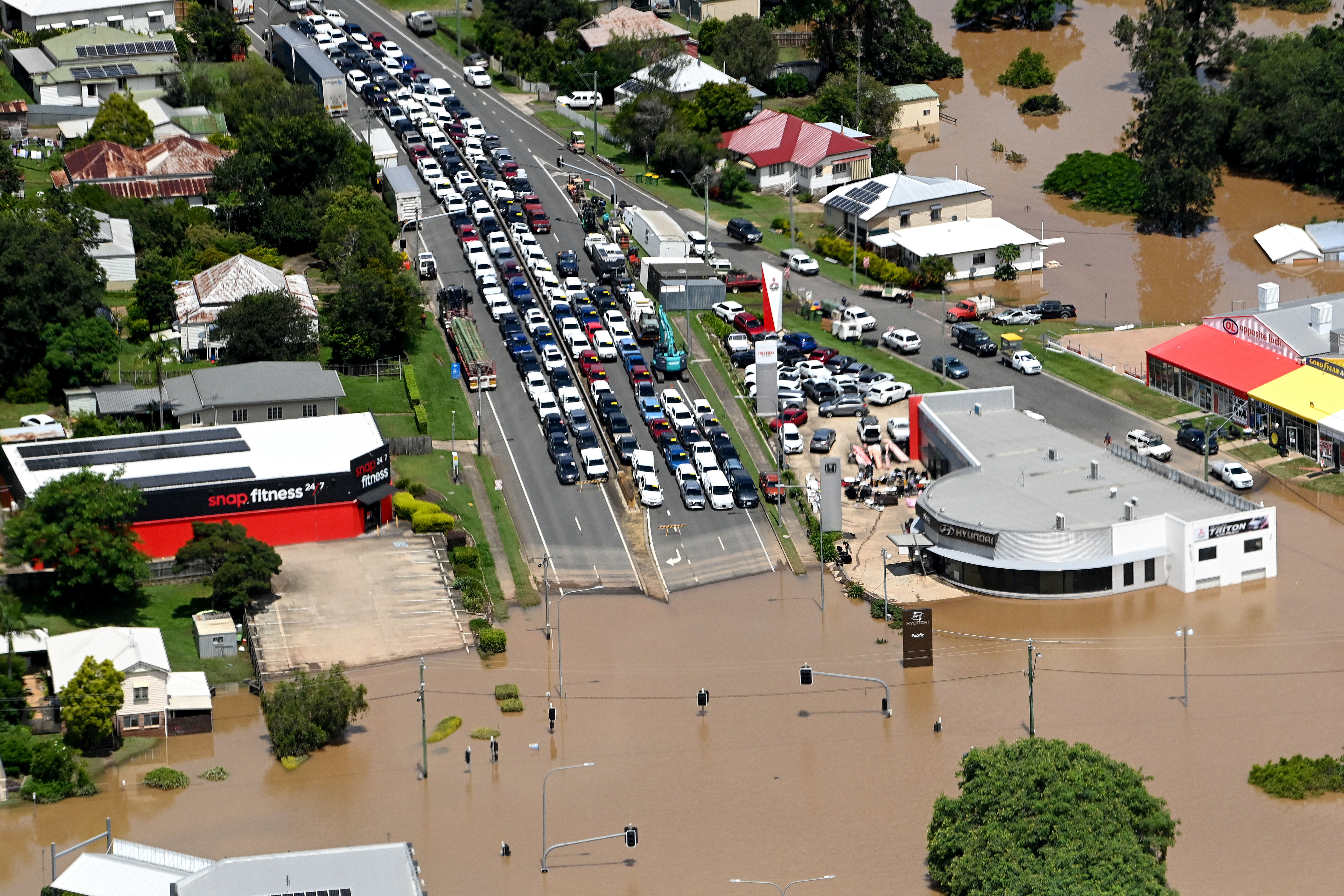 In an aerial view, vehicles are seen stuck along a street as floodwaters surround Gympie, in Queensland's south-east. Image: Bradley Kanaris/Getty Images