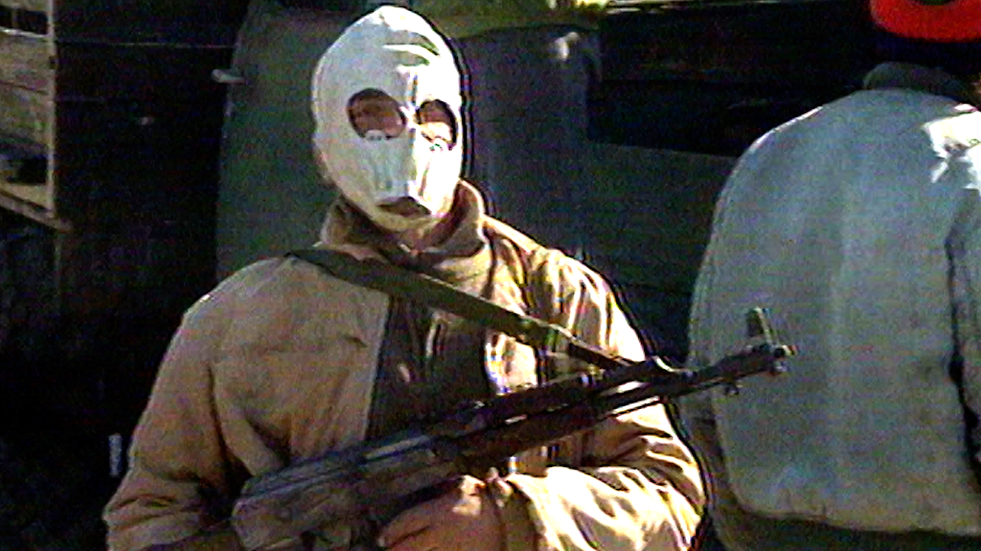 A member of the paramilitary drug trafficking gang The Clan del Golfo wears a mask and holds a Kalashnikov assault rifle.