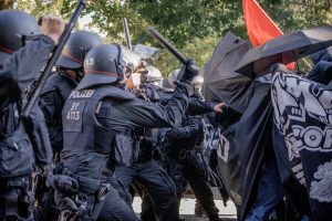 Polizisten mit Helmen und Schlagstöcken stürmen auf Demonstrierende