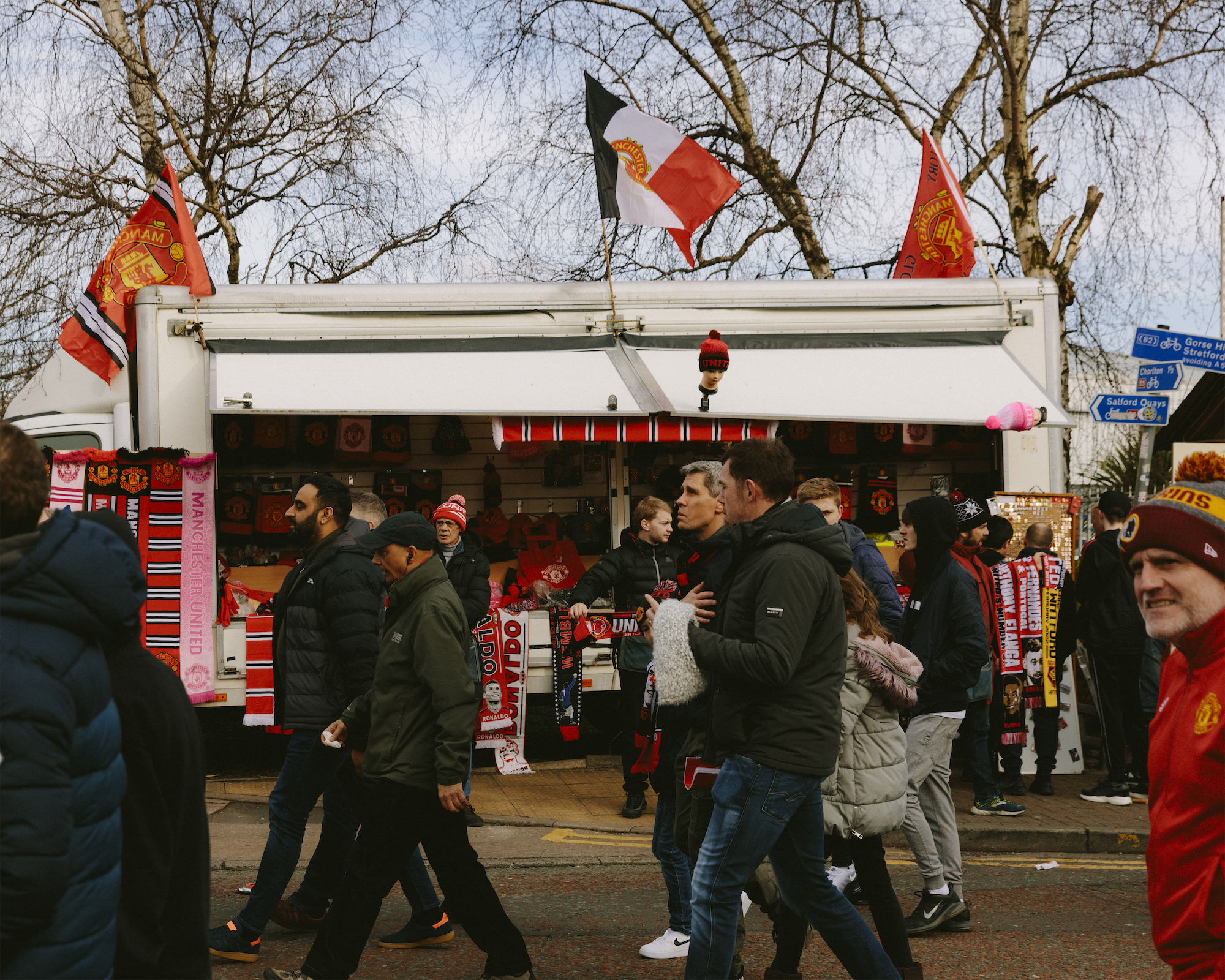 Manchester United fans march past a merch stall on Sir Matt Busby Way