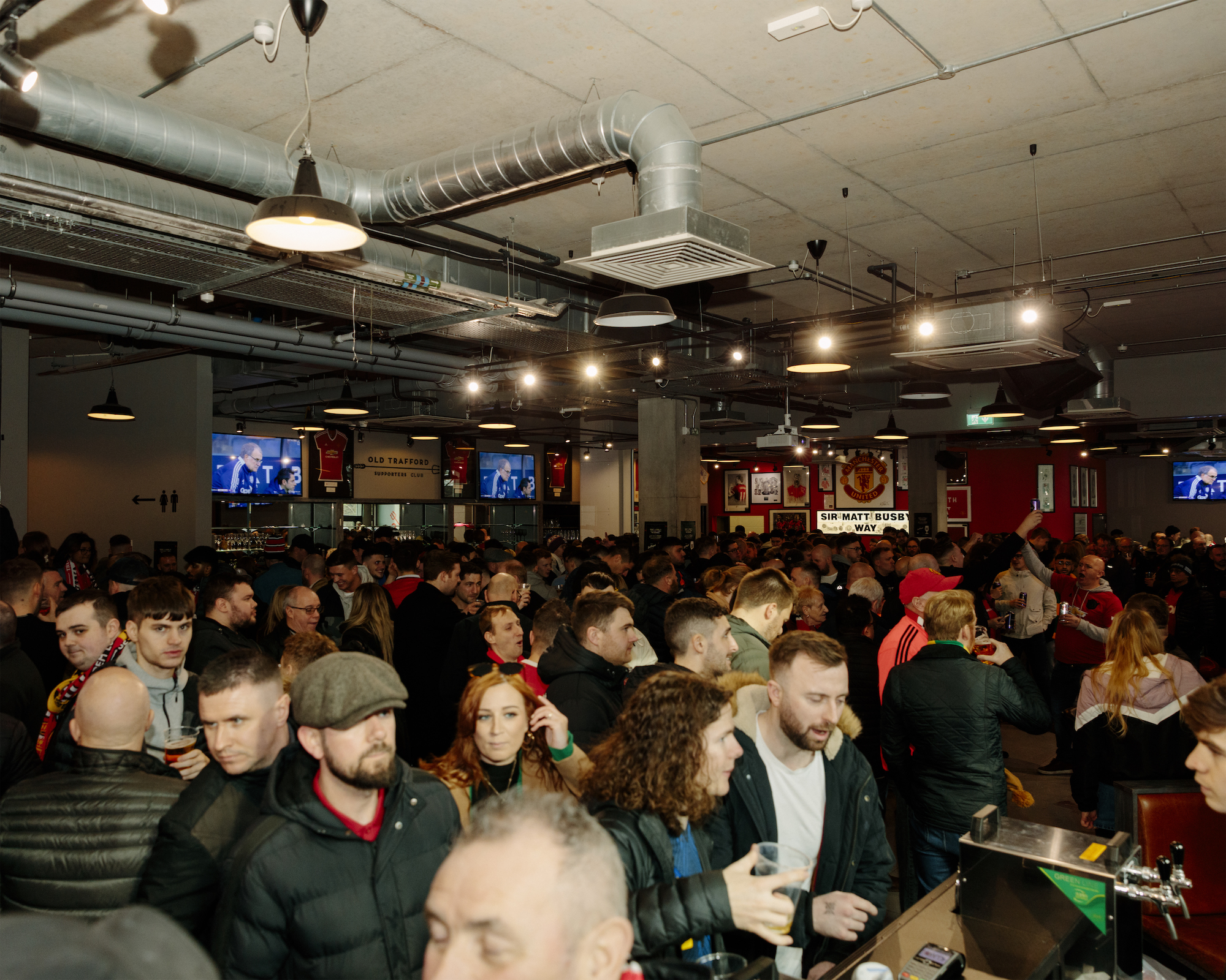 Manchester United supporters queue for pints at the Old Trafford Supporters' Club.
