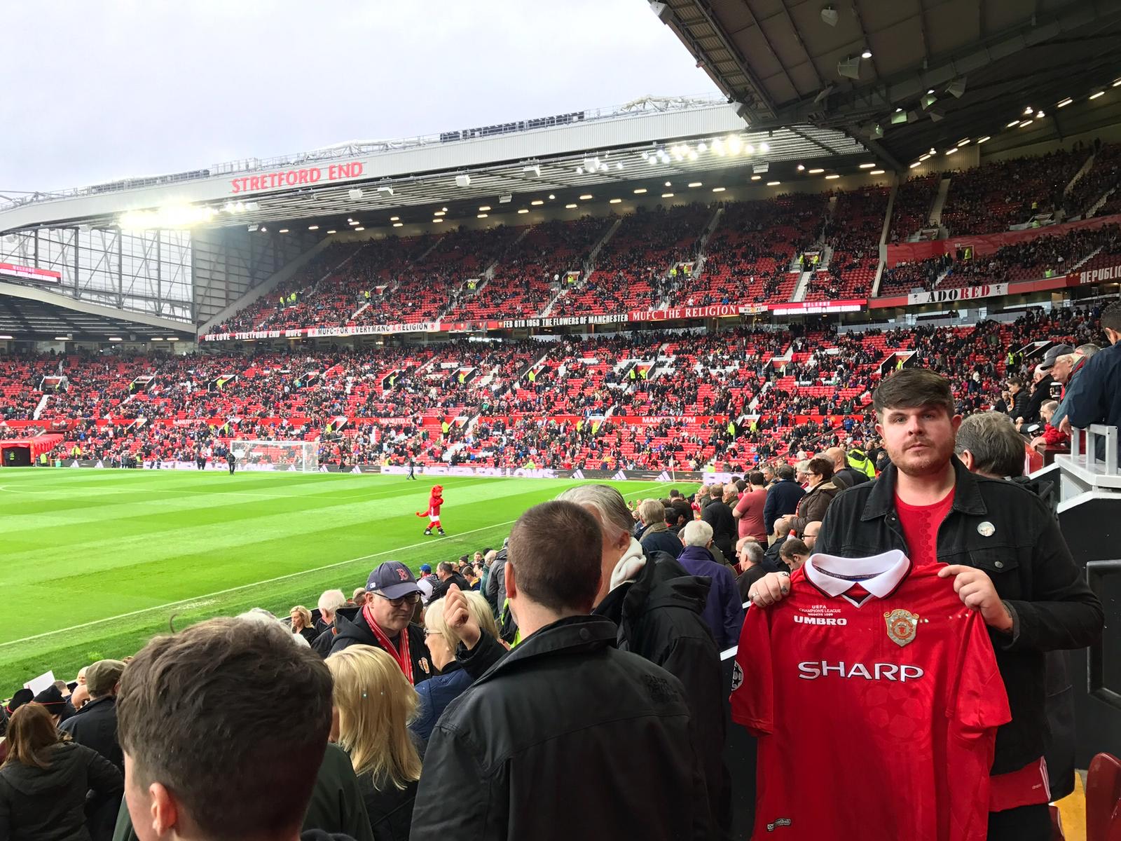 Manchester United supporter holding up his dad's shirt at a stadium game