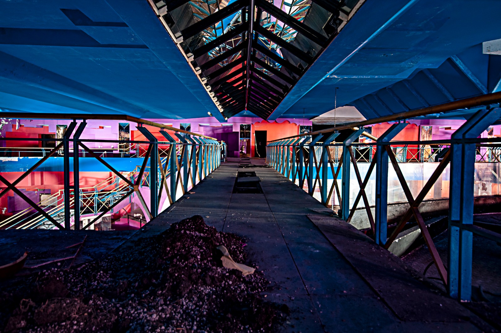 Italian Club Urbex, Woodpecker – A suspended bridge with skylights on top. The walls are painted in very bright lilac and red tones.