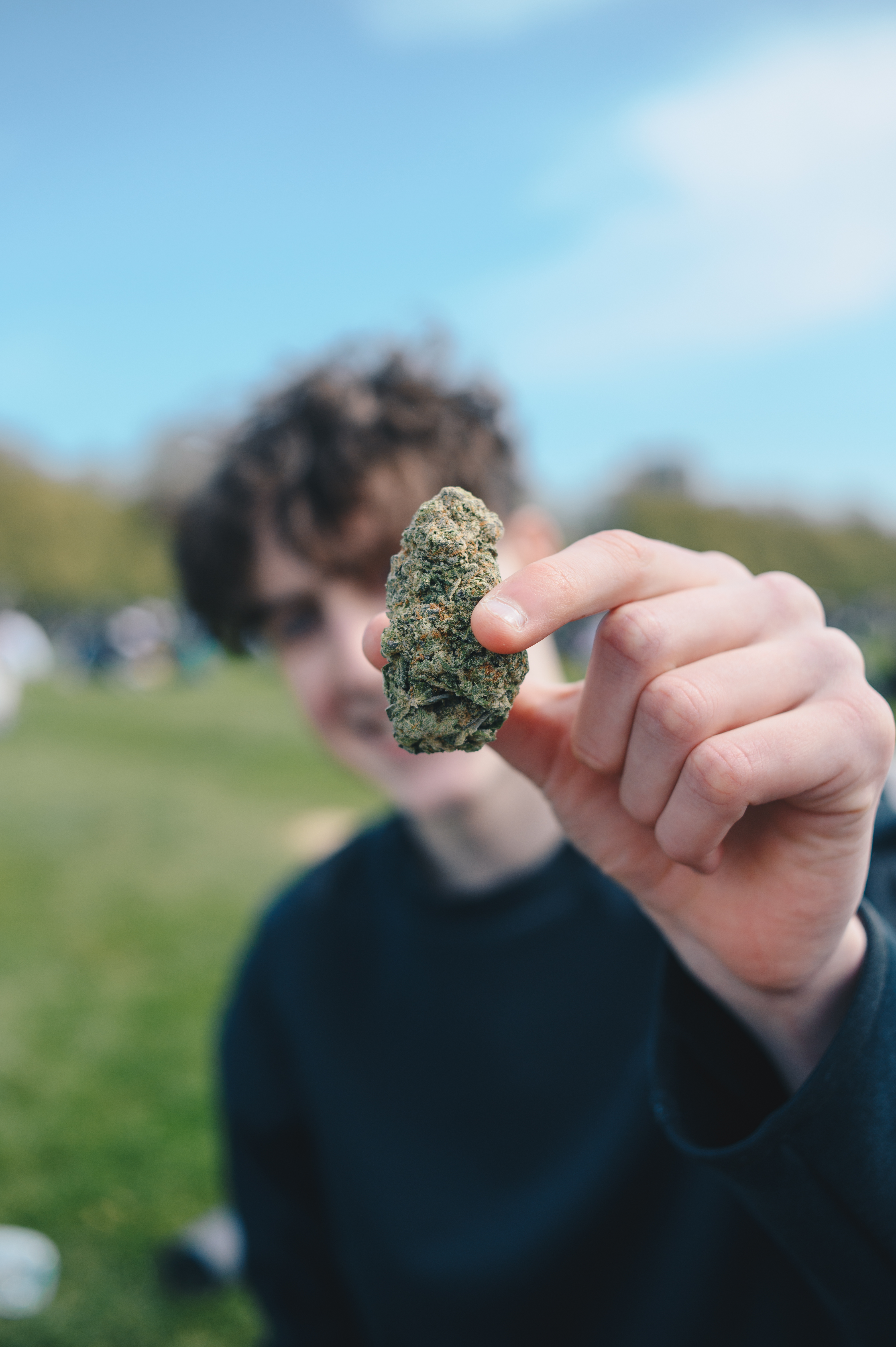 A person with curly hair holds up a nugget of weed at 4/20 protest in London Hyde Park