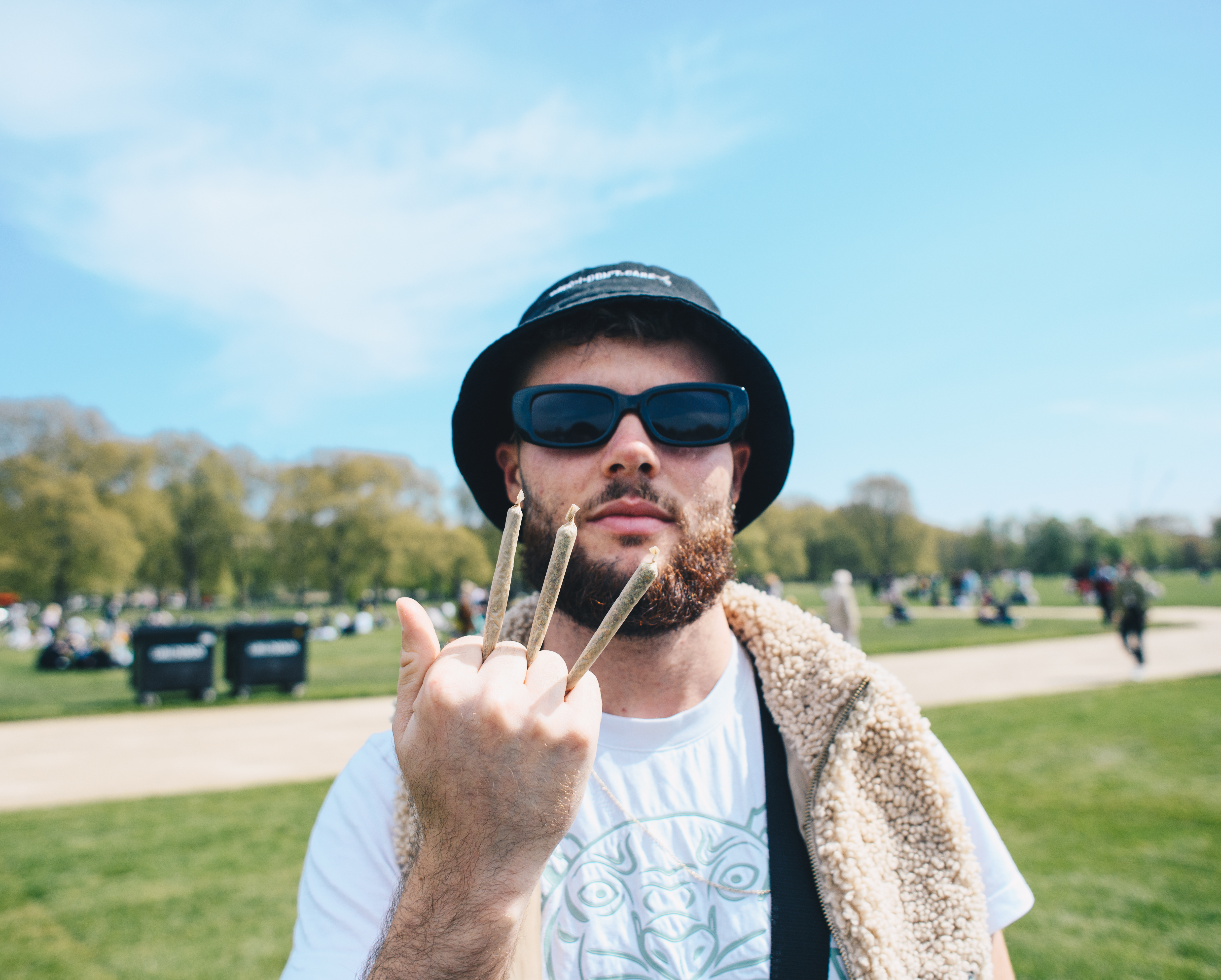 A man in a bucket hat holds up three spliffs like Wolverine claws at 4/20 protest in London Hyde Park