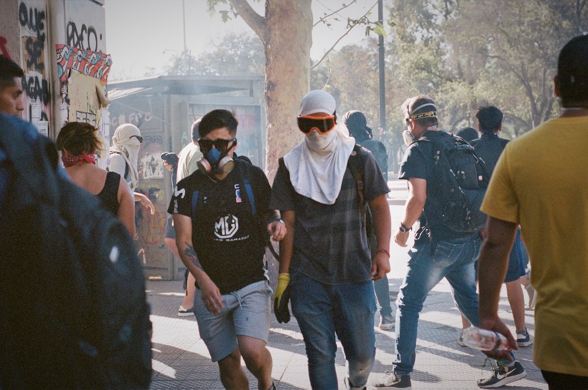 Chile protests – A group of young people wearing gas masks, sunglasses and goggles, walking in different directions.