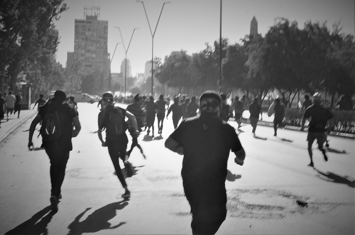 Chile protests – black and white photo of people running in different directions.