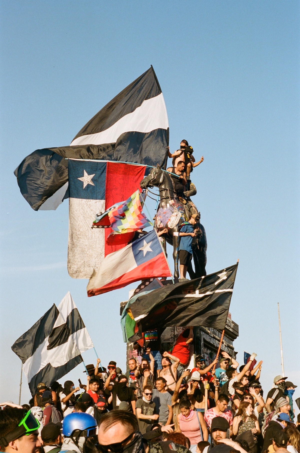 Chile protests – protesters climbing up on a tower and waiving different flags.