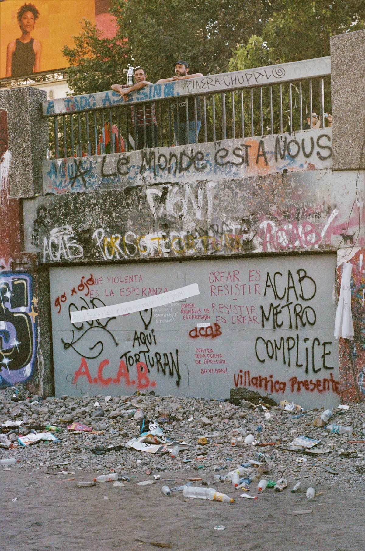 Chile protests – two guys looking over a bridge full of graffiti.
