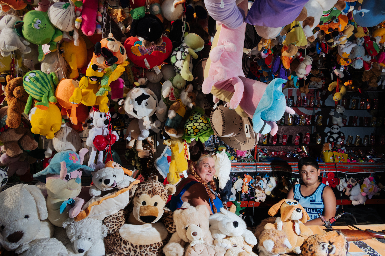 Michele Battilomo, De-population, Basilicata – Child and woman at a carnival stand surrounded by soft toys.