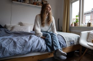 A depressed young person sat on their bed
