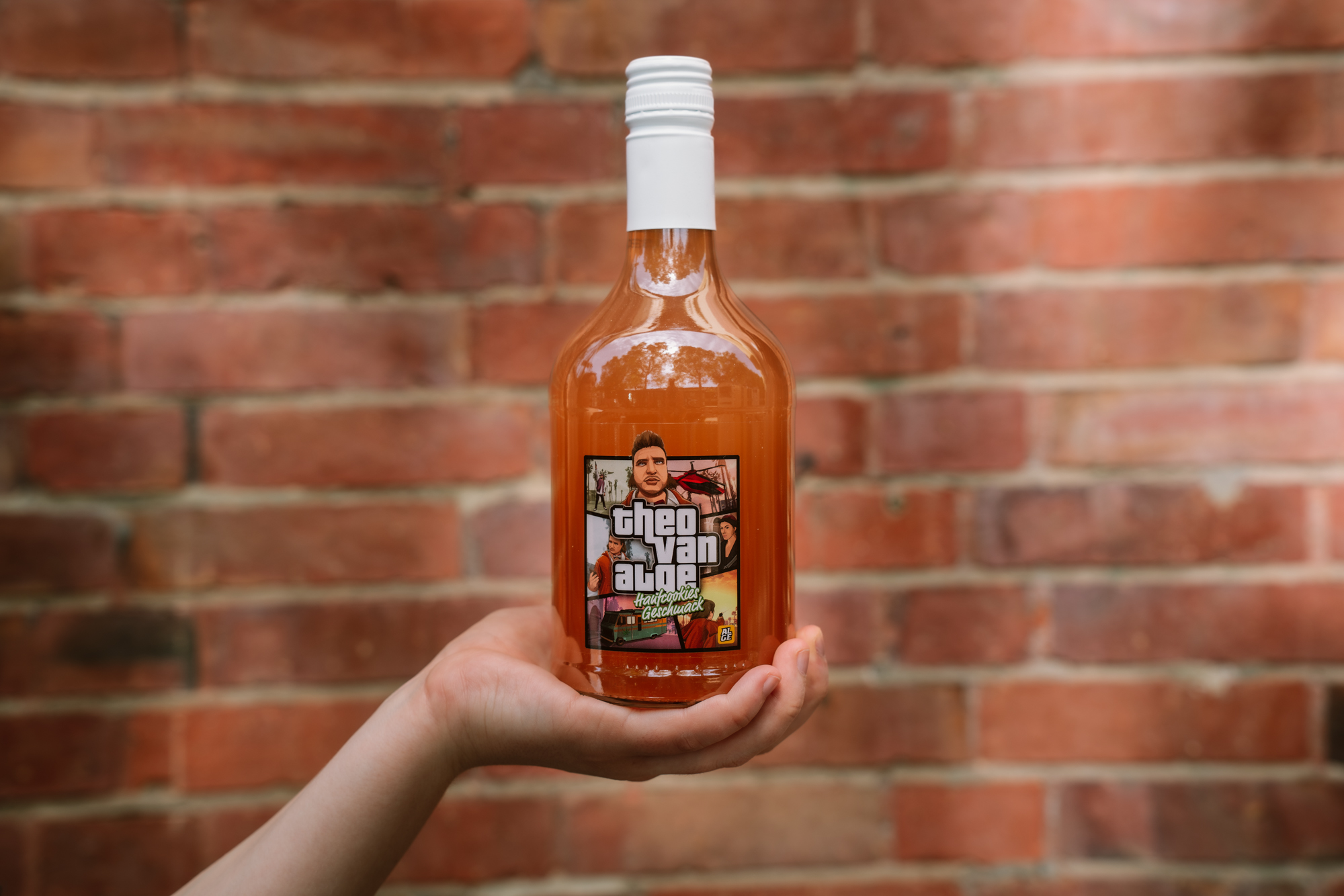 Die Autorin hält eine Flasche von Knossis Hanfcookielikör vor eine Backsteinwand.
