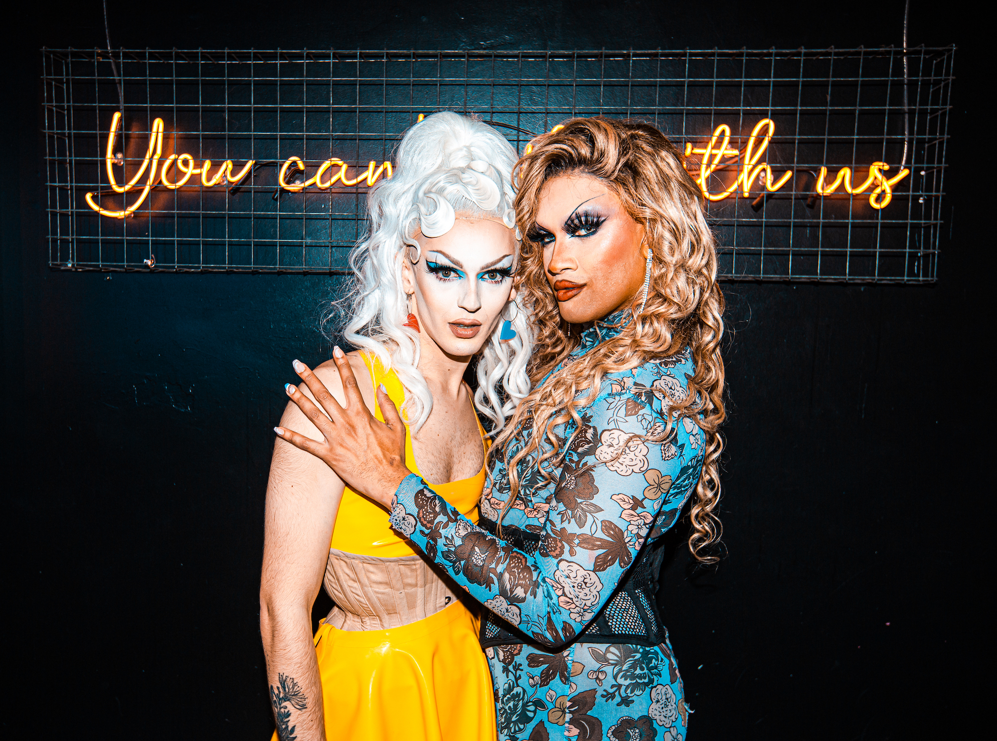 Drag queens Karma Doll and Soraya Marchelle posing in front of a Mean Girls sign at the Queen of Hoxton drag brunch