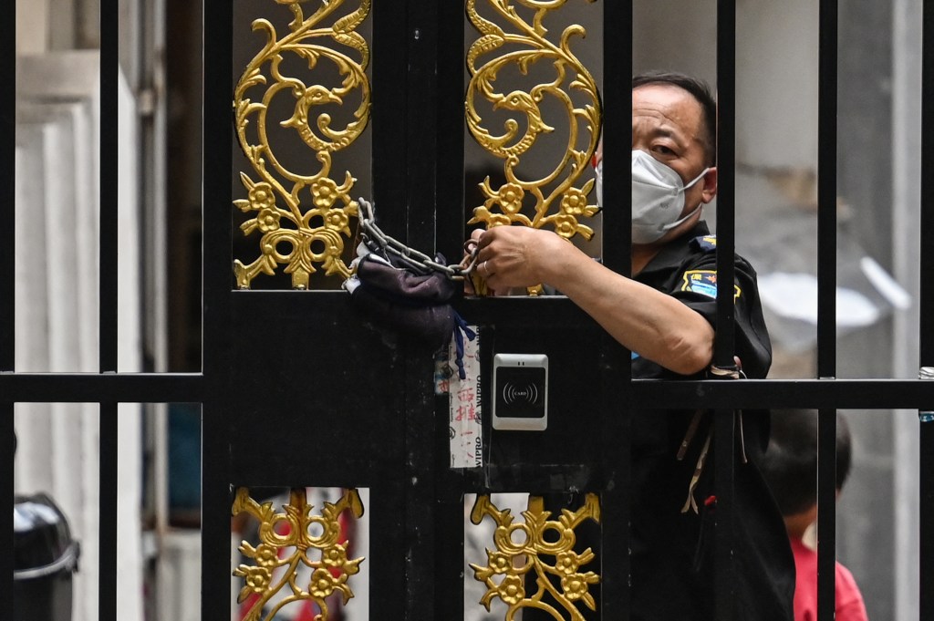 A SECURITY GUARD IN SHANGHAI SEALING A HOUSING ESTATE SHUT DURING THE PANDEMIC. PHOTO: HECTOR RETAMAL/AFP
