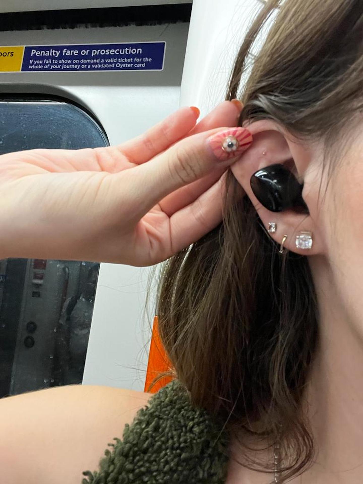 A photo of the author wearing ear seeds on the tube during rush hour.