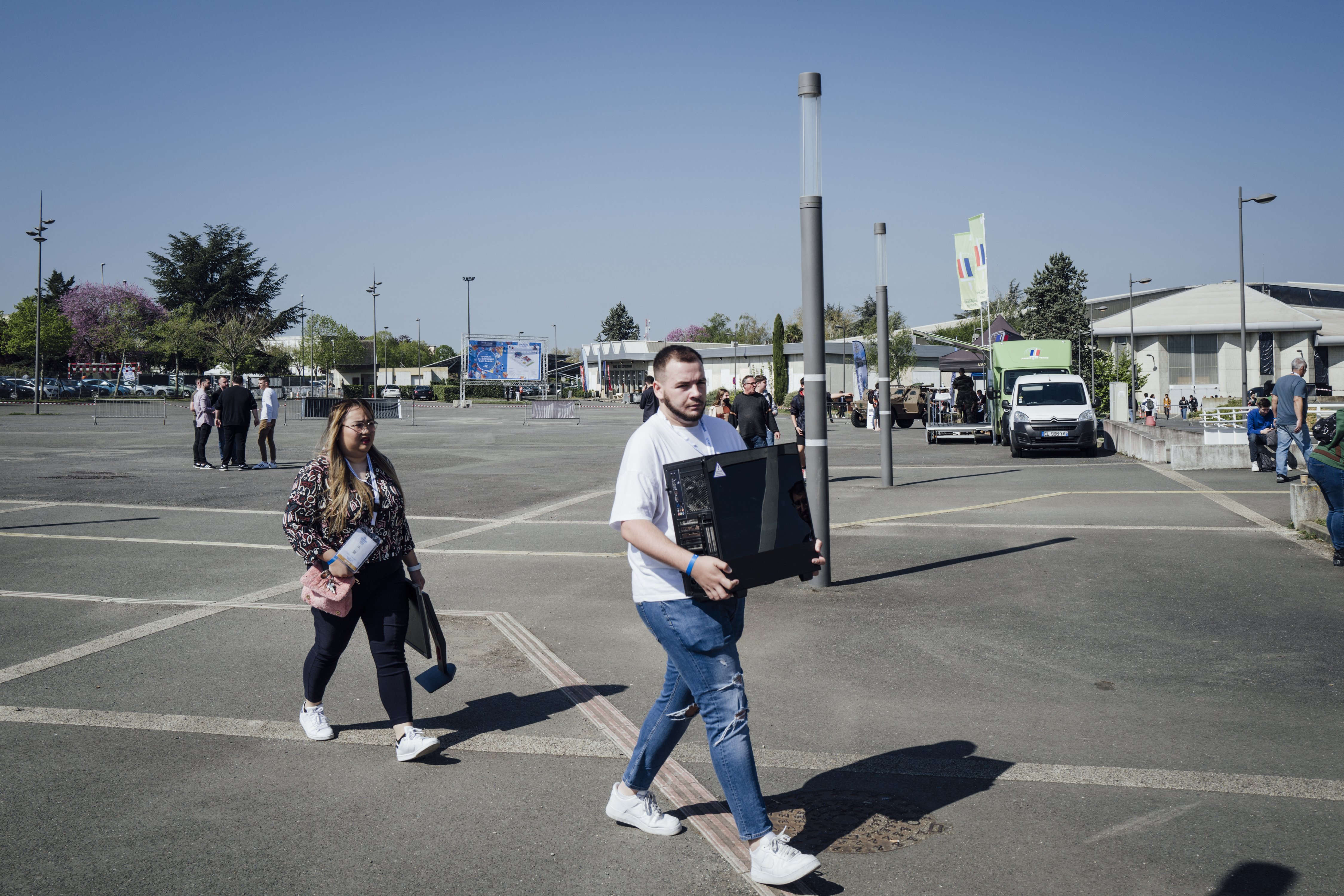 Gamers Assembly, LAN party – Photo of the parking lot in front of the hangars, with people walking across it, carrying equipment.