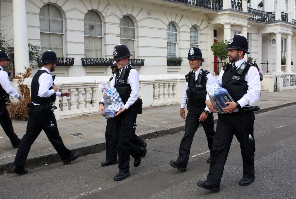 Police officers carry confiscated canisters of nitrous oxide during Notting Hill Carnival in 2022