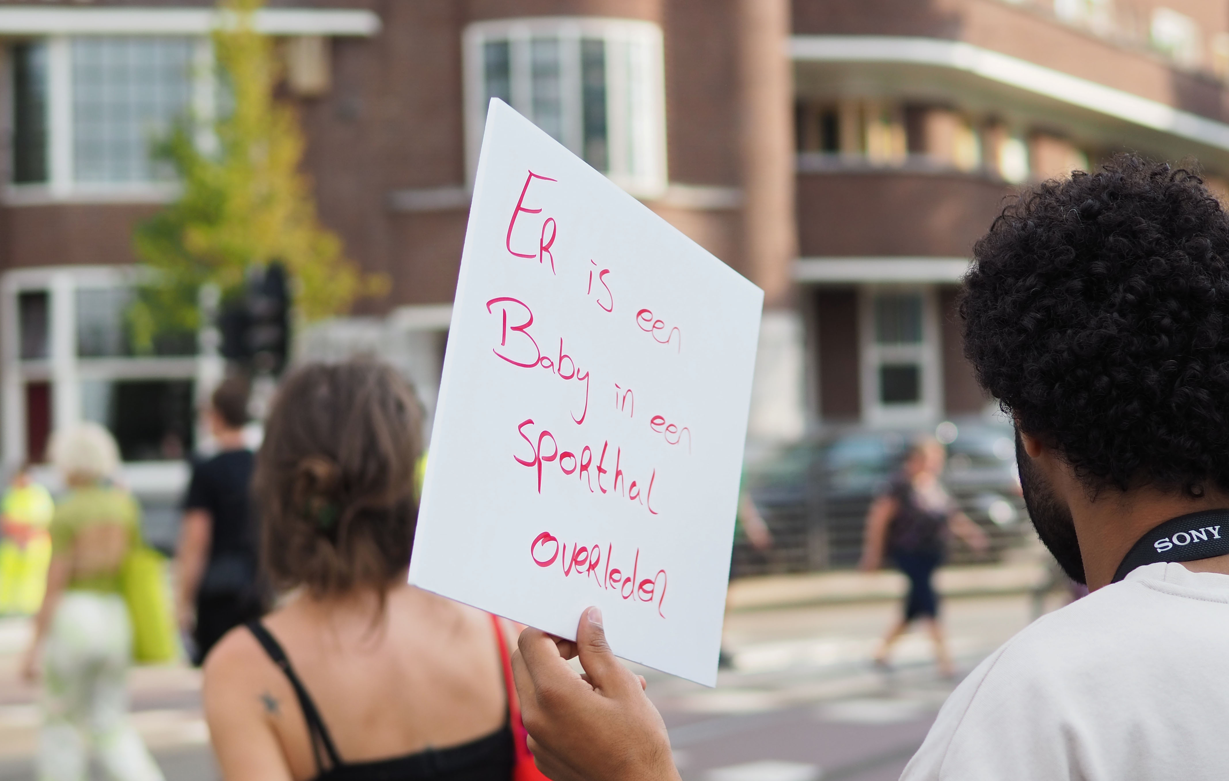 Netherlands refugee crisis, Ter Appel, protest – protester holding sign written in red felt tip on a white piece of cardboard