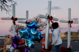 A Walmart employee signs a note on a wooden cross near the site of a shooting at the store on November 28, 2022 in Chesapeake, Virginia.