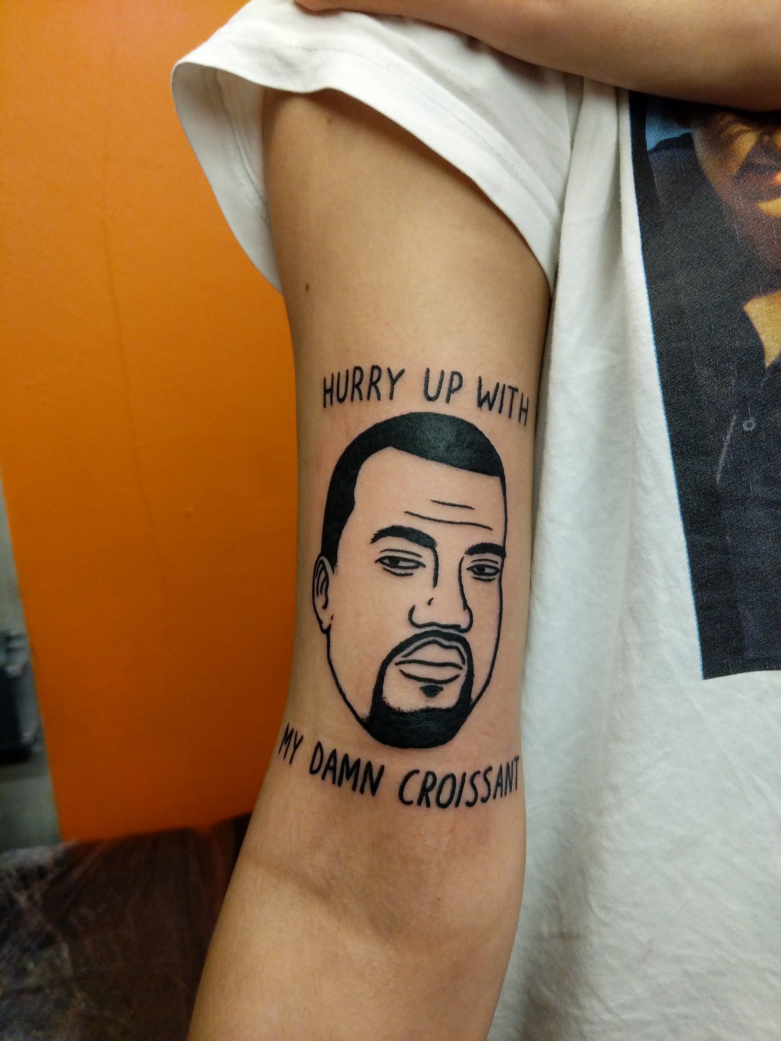 An arm showing a Kanye West face tattoo