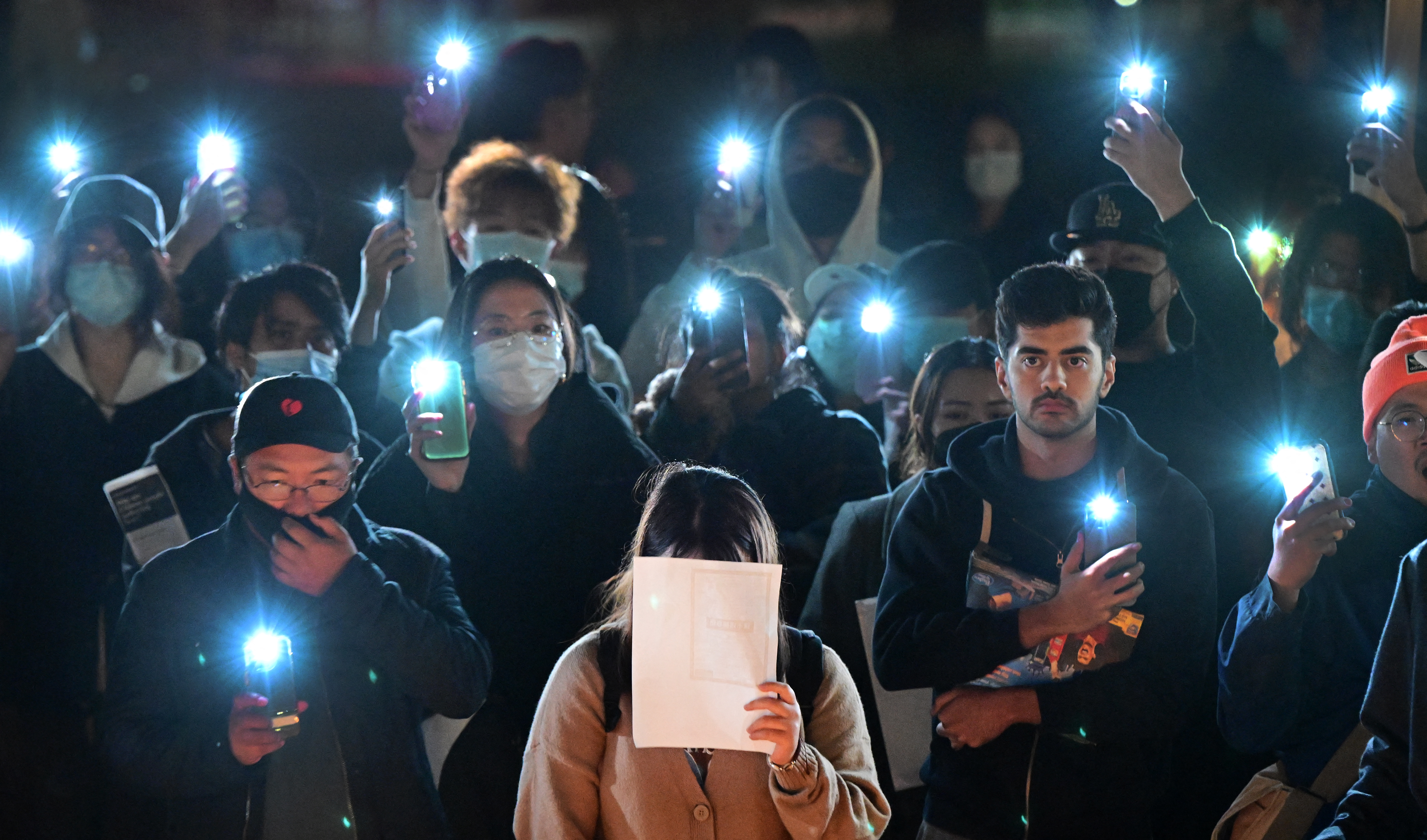 A WOMAN HOLDS UP A BLANK PIECE OF PAPER, a symbol of recent protests in China, AT A RALLY IN IRVINE, CALIFORNIA. PHOTO: FREDERIC J. BROWN / AFP