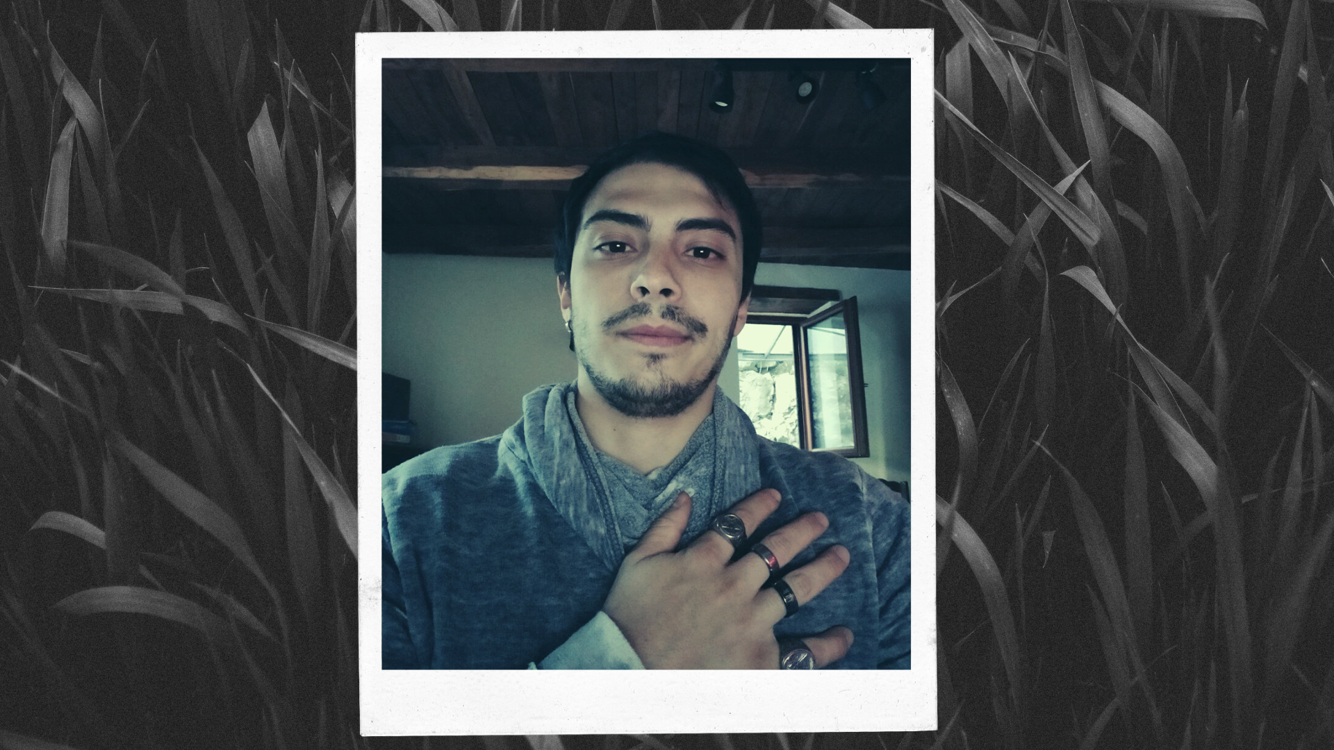 Eugenio, Unione Satanisti Italiani - young man with short black hair, black eyes, a moustache and a goatee. he is wearing a grey sweatshirt and many silver rings on his right hand which is resting on his shoulder.